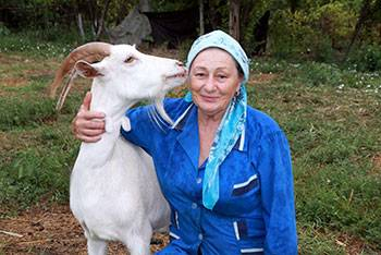 o fotografie a unei femei din sat cu o capră