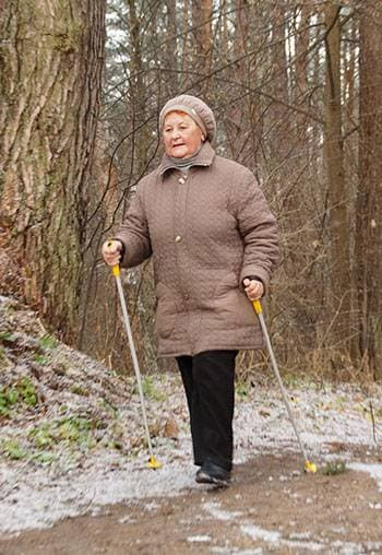 o femeie în vârstă face mers nordic pe stradă